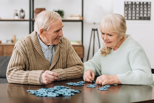 happy-retired-couple-playing-puzzles-home